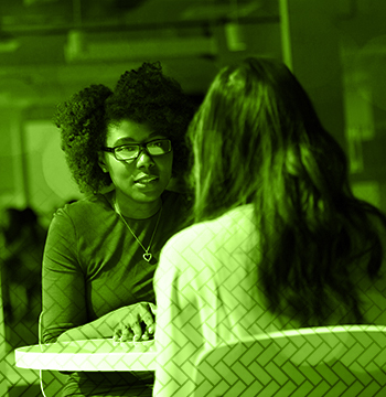 Two young women at a table conversing.