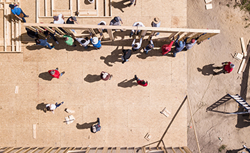 A group of people holding up framing on a house construction site.