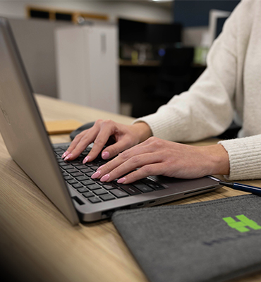A woman's handing typing on a laptop.