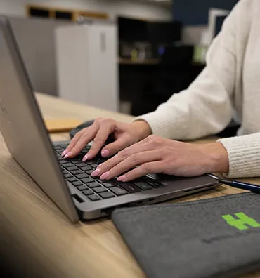 A woman's handing typing on a laptop.