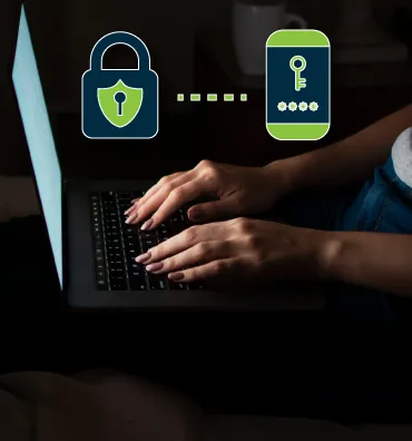 Two icons representing security over the hands of somebody using a laptop.