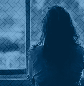 A person looking out a window with their back facing the viewer.